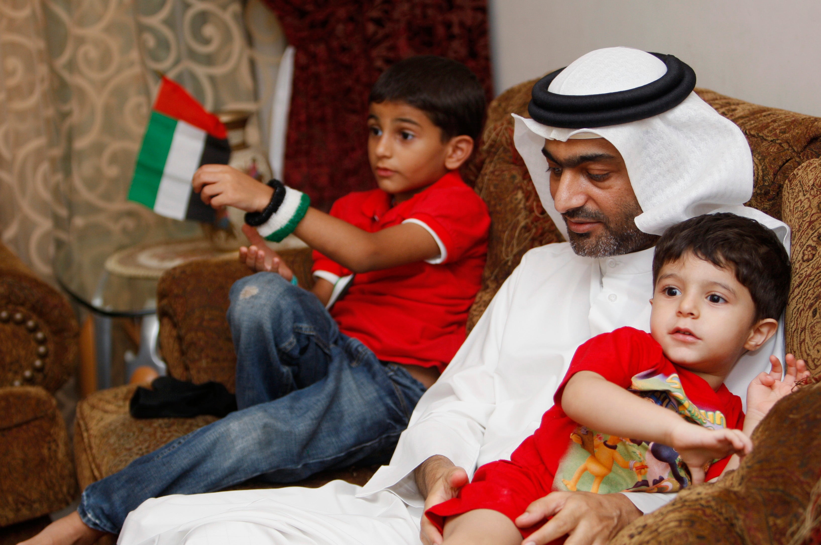 A man sits on a couch with two boys