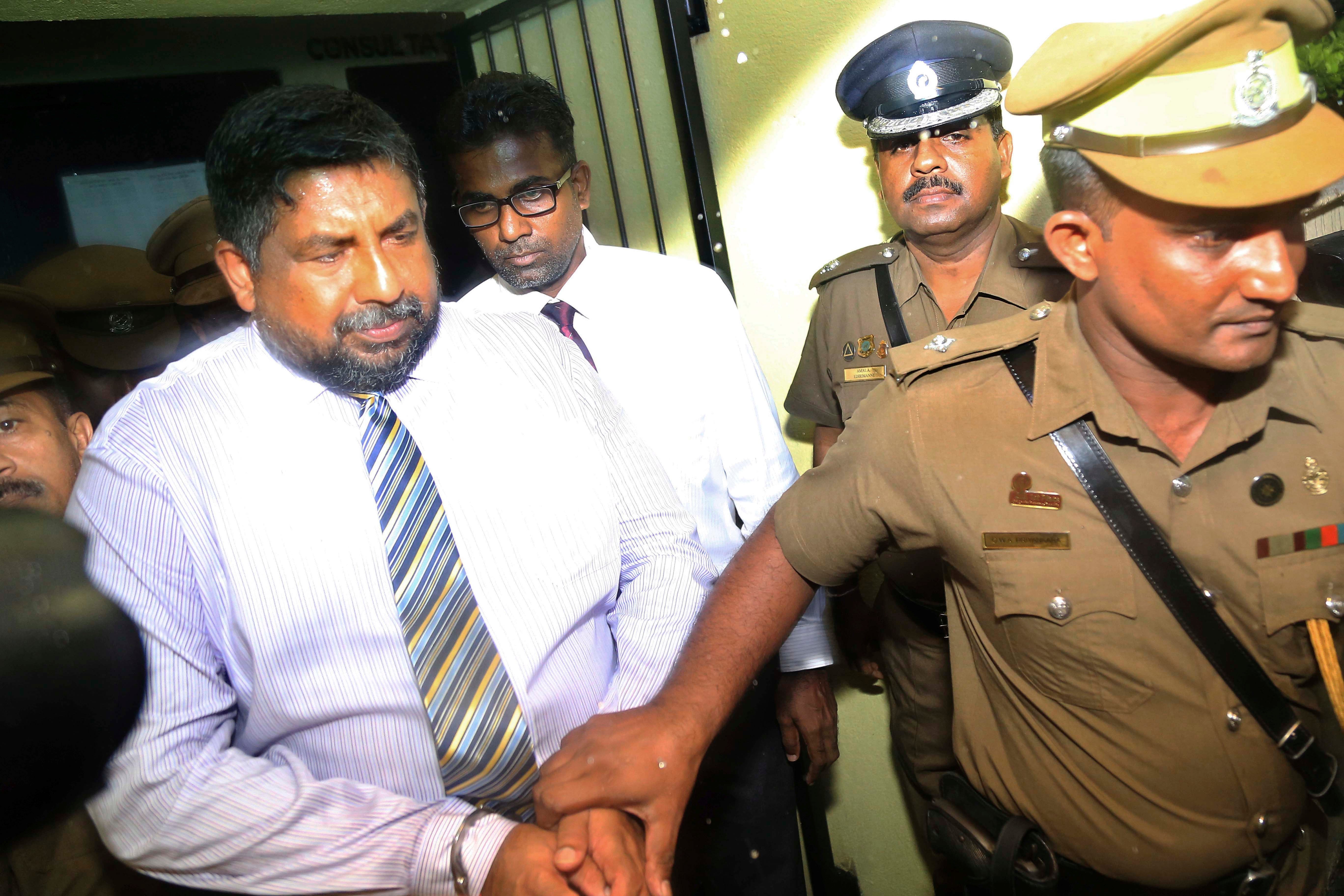 A policeman escorts a man in handcuffs