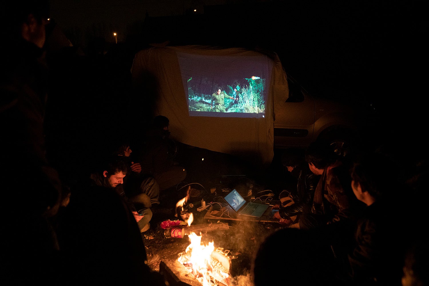 A group of Afghan boys and young men watch a movie screened by a volunteer at their encampment on the outskirts of Calais, northern France, September 2020.