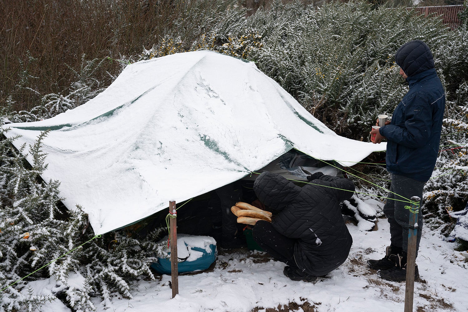 Volunteers distribute food and tea to a group of Afghan boys at a migrant encampment in Calais, northern France, February 2021.