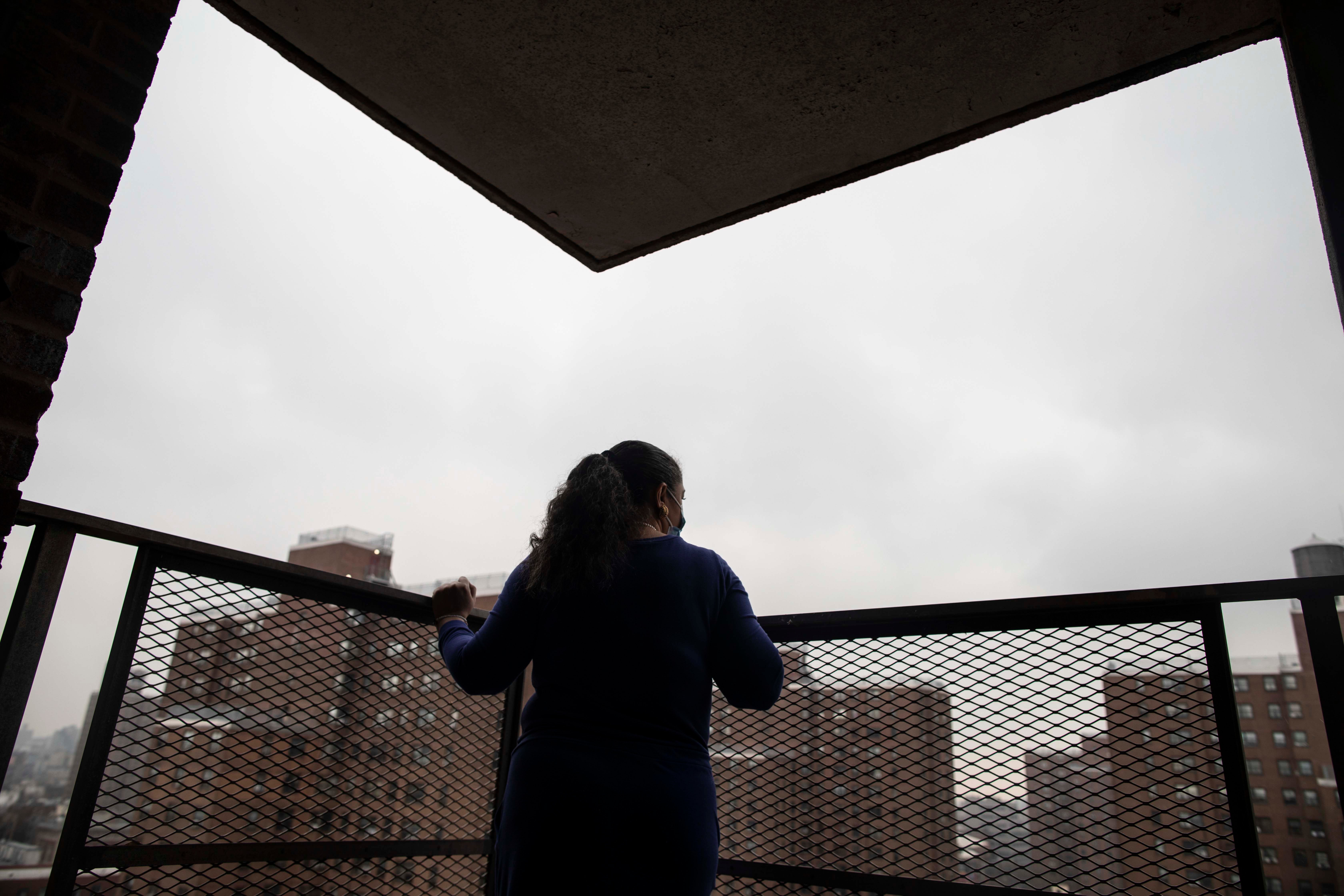A woman looks out at a city from a patio