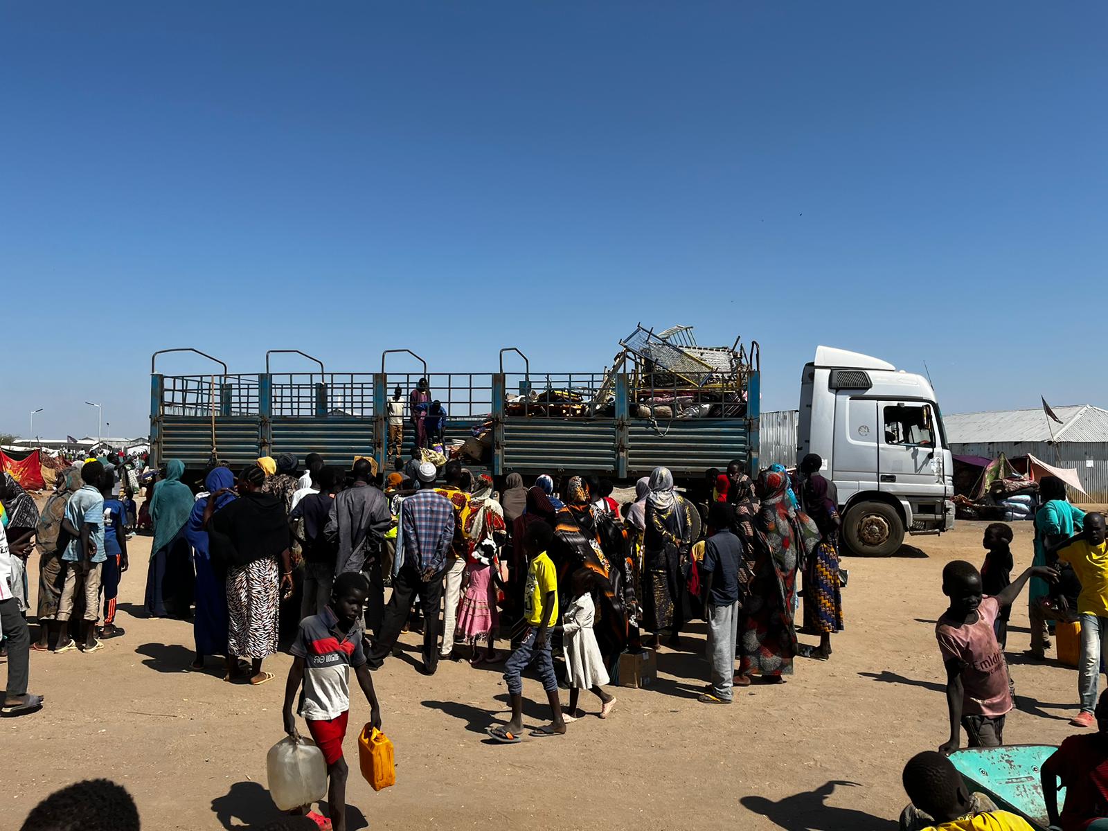 Des personnes sortent d'un camion qui les a amenées de la frontière avec le Soudan au centre de transit de Renk, au Sud-Soudan ; on ne voit que quelques valises et des barreaux de lit.