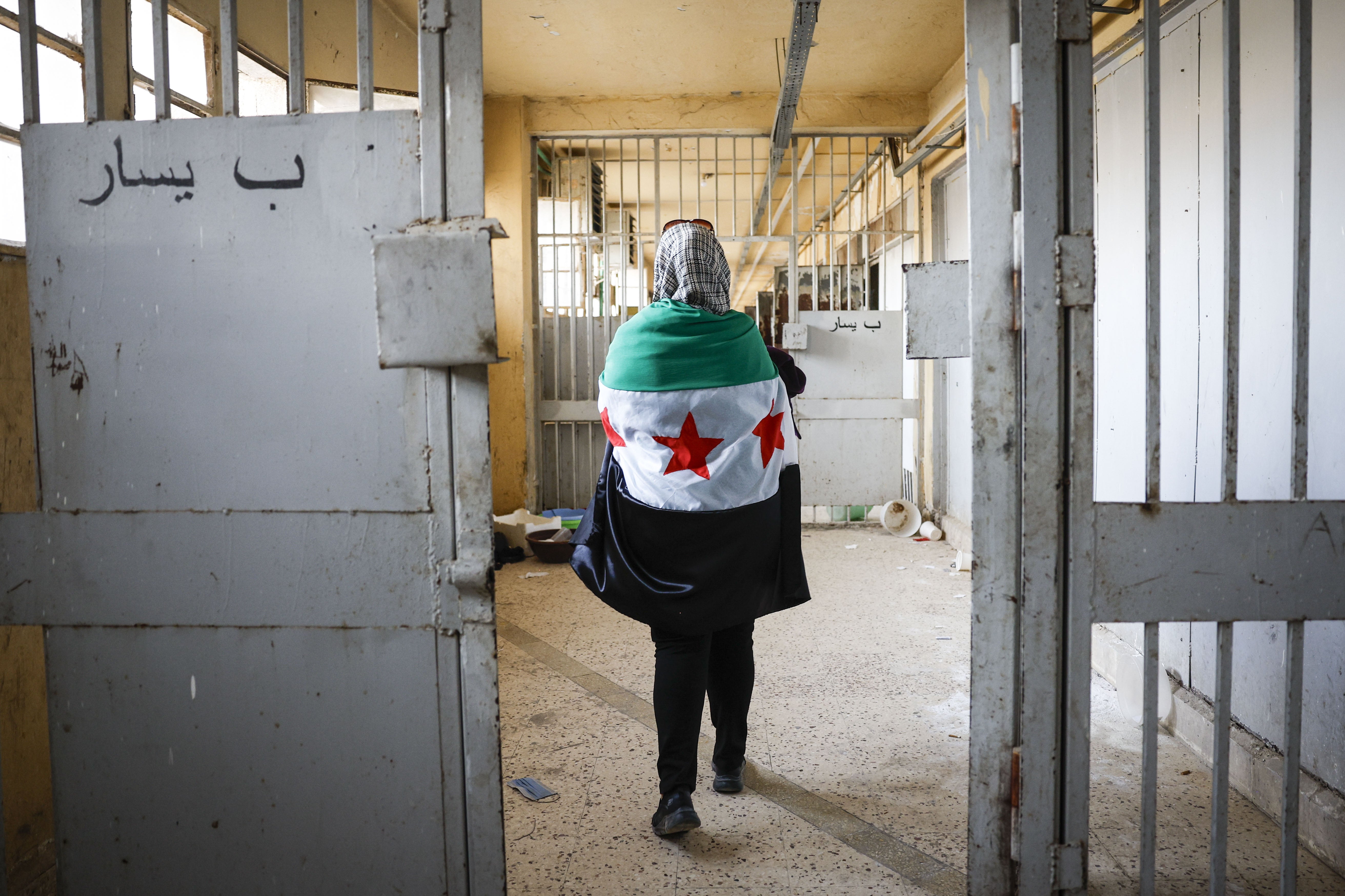 A woman wearing a Syrian opposition flag visits Sednaya prison near Damascus, Syria, December 12, 2024