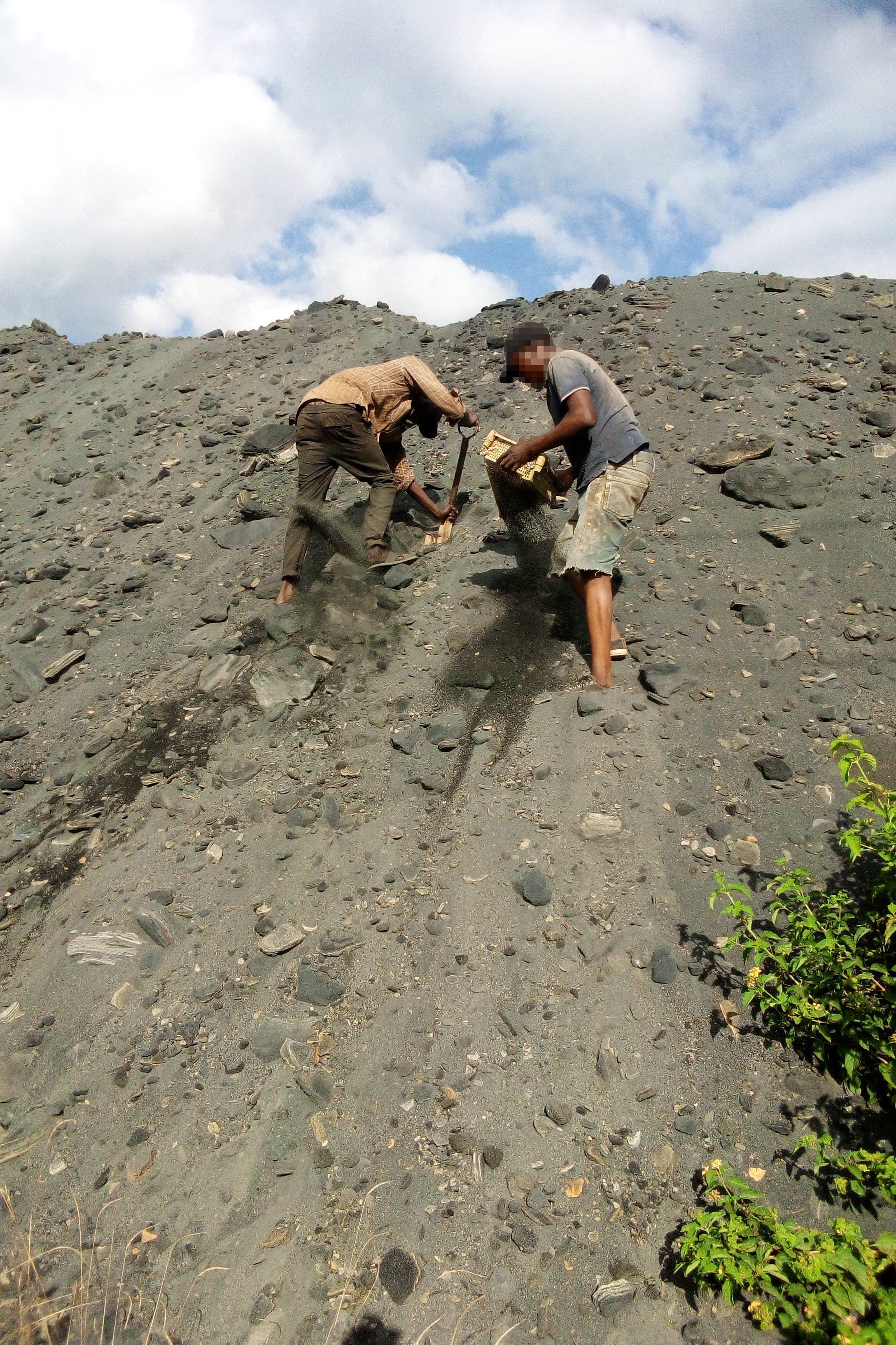 Two miners demonstrate to members of a local civil society organization how they dig for zinc and other minerals in lead waste