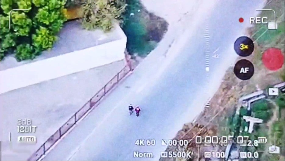 Screengrab of a drone video showing two people walking down a street