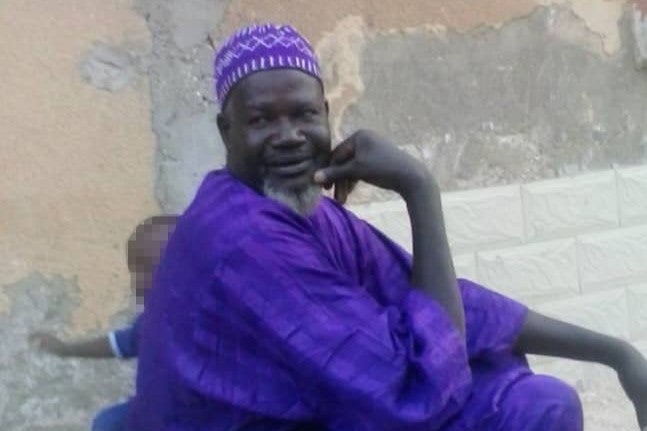 A man in purple clothes sitting next to a child
