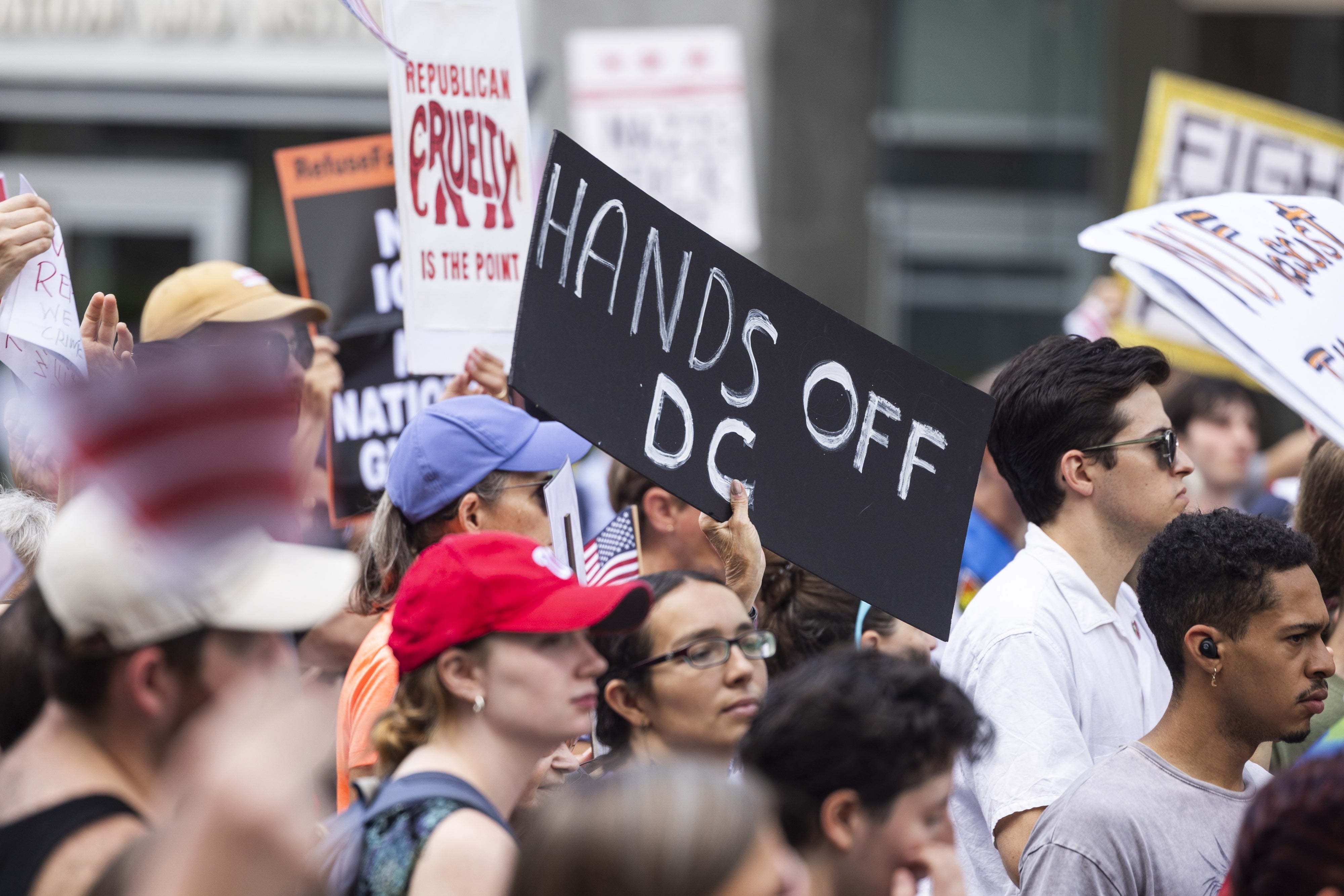 A person holds a sign that reads "Hands off DC" at a rally 