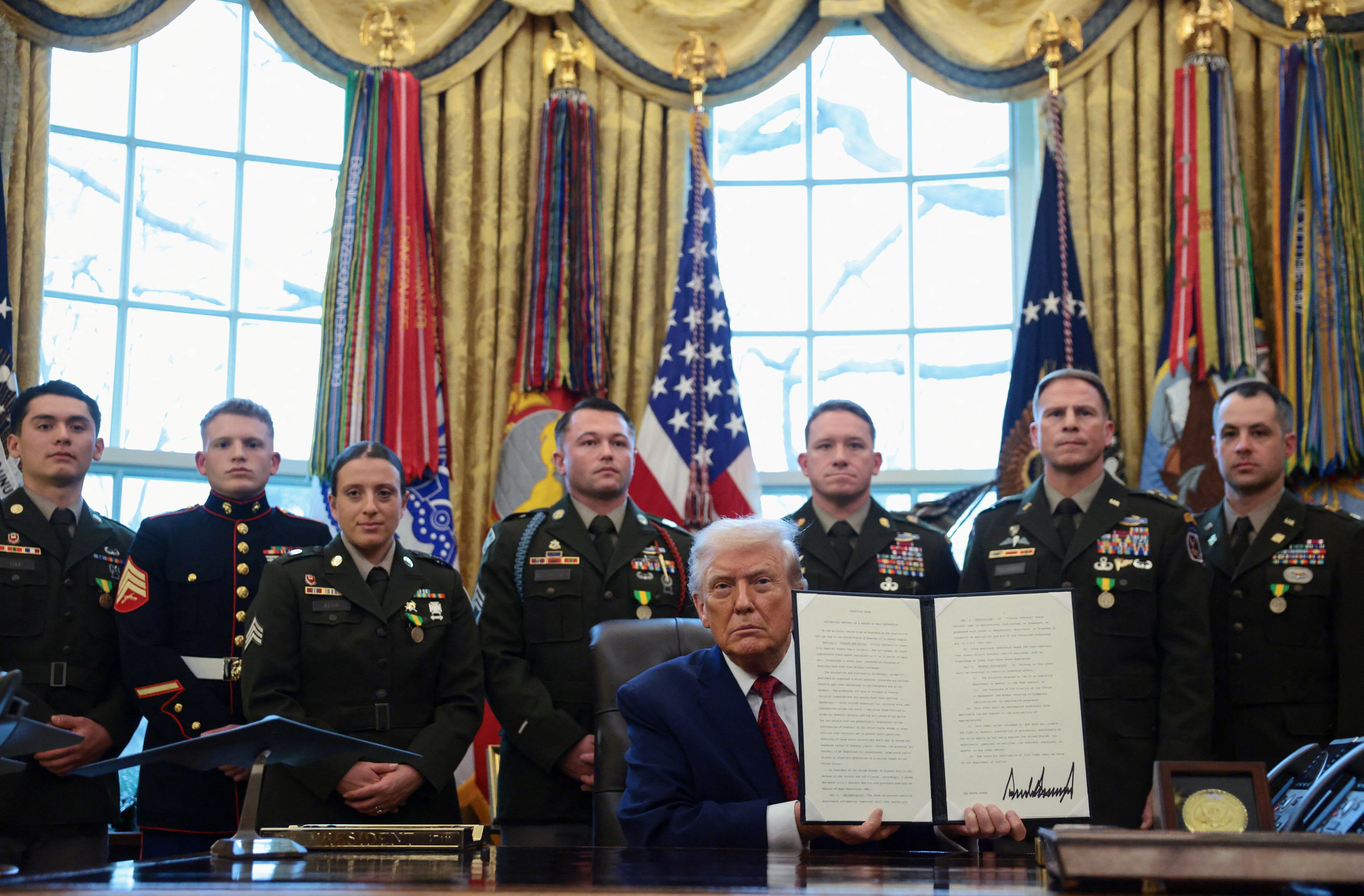 US President Donald Trump shows a signed executive order classifying fentanyl as 'weapon of mass destruction' during a Mexican Border Defense Medal presentation in the Oval Office at the White House in Washington, DC, December 15, 2025.