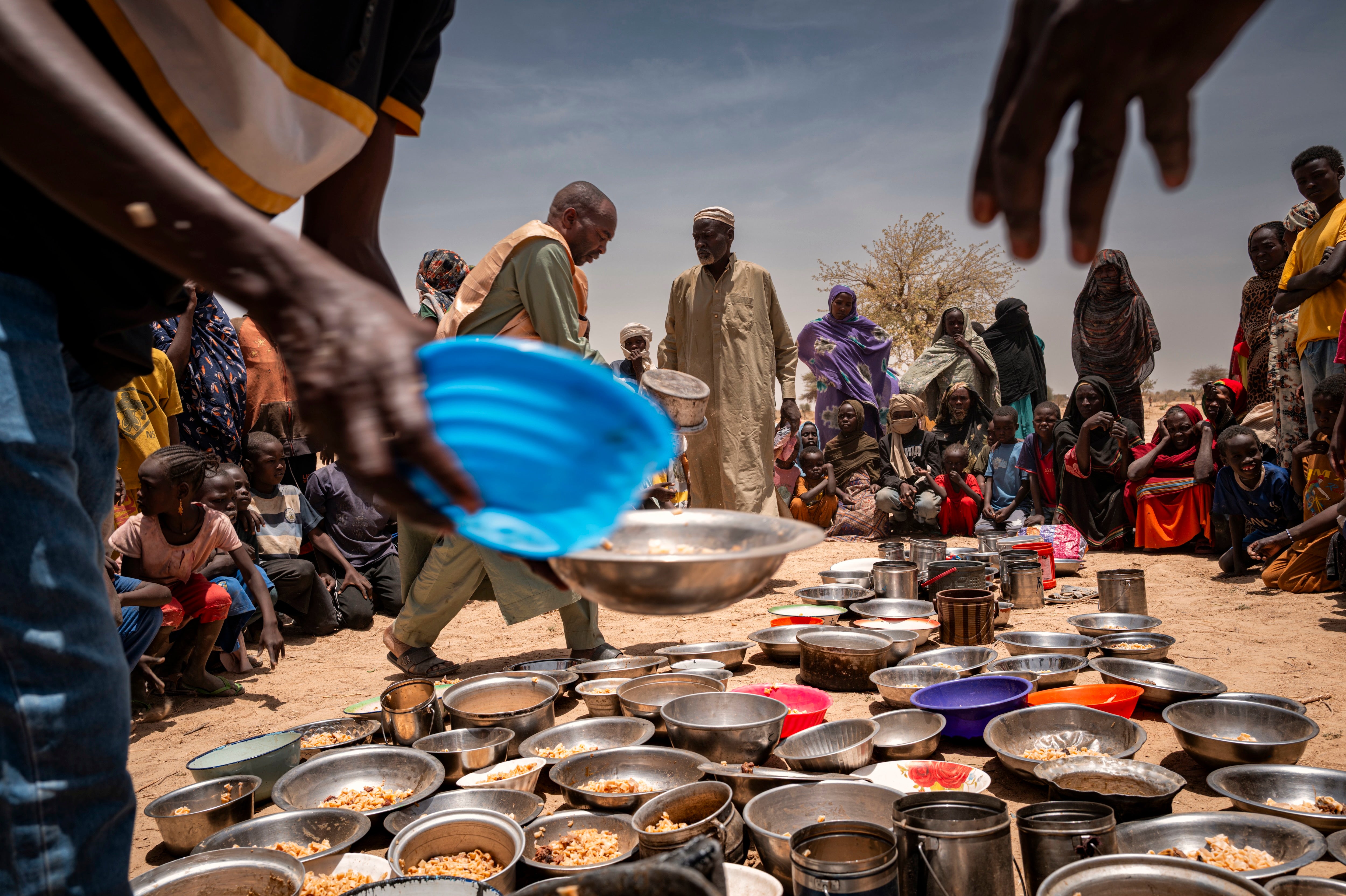 Sudanese refugees from Zamzam camp outside of El Fasher, in Darfur, receive food at an Emergency Response Room Communal Kitchen while being relocated to the Iridimi transit camp in Tine, eastern Chad, May 4, 2025. 