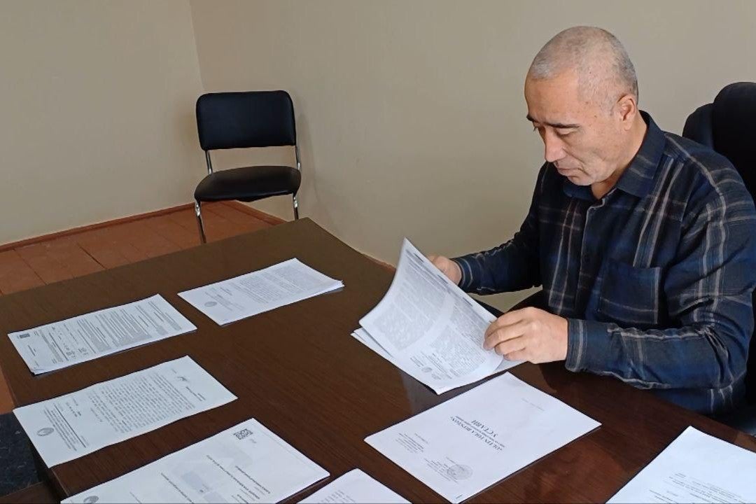 A man reviews documents seated at a desk