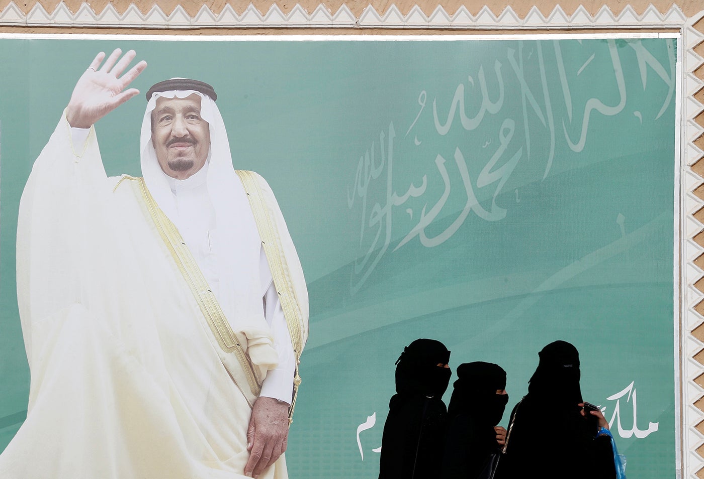 Women walk past a poster of Saudi Arabia's King Salman bin Abdulaziz Al Saud during Janadriyah Cultural Festival on the outskirts of Riyadh, Saudi Arabia February 12, 2018. 