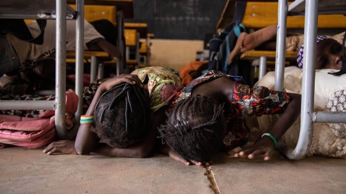 Young girls hide under a desk