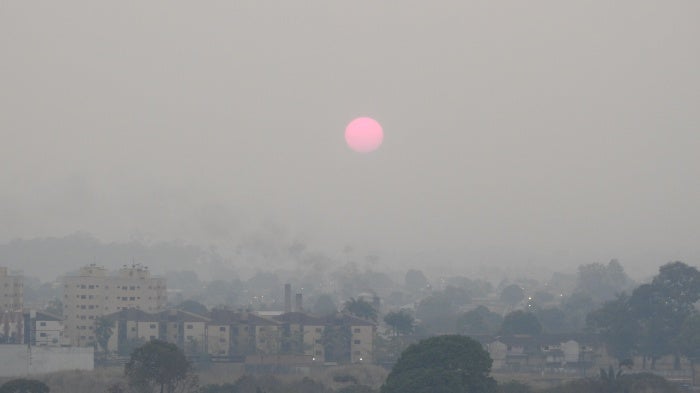 The sun rises over a city skyline covered in smoke