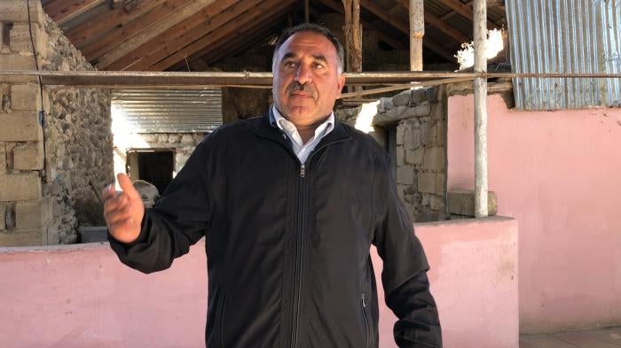 Man is interviewed in front of ruin