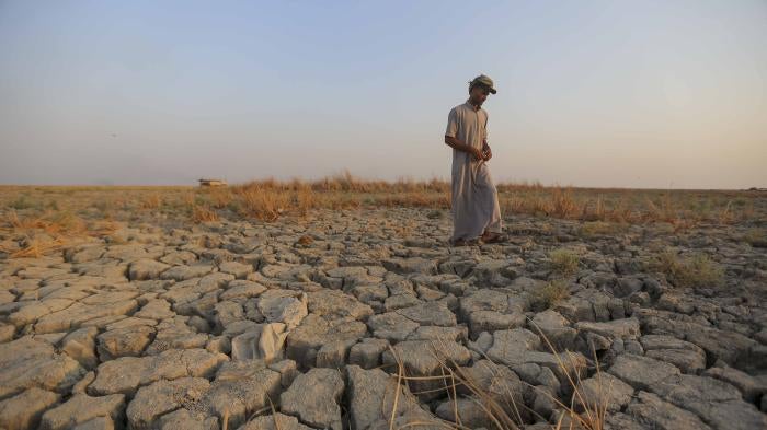 A fisherman walks across a dried patch of land in the marshes of southern Iraq in Dhi Qar province, September 2, 2022. Iraq's marshlands are rapidly receding due to drought, domestic water mismanagement, and diversion from neighboring countries.