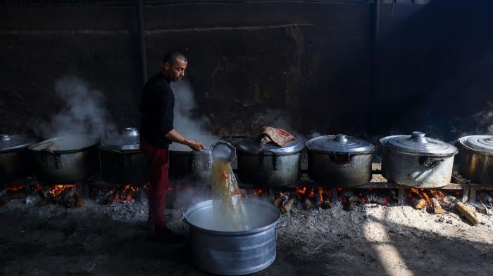 Palestinians prepare meals at a UN shelter to be distributed to displaced people in Rafah, in the southern Gaza Strip, October 23, 2023.
