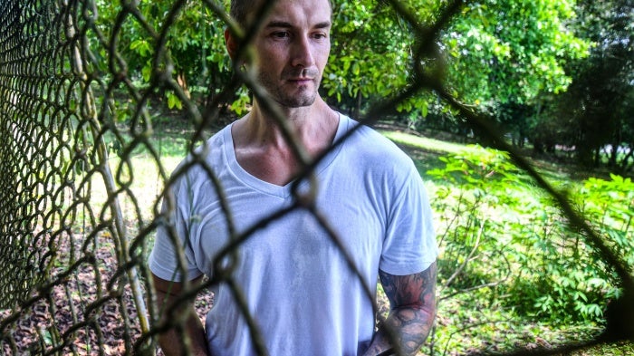 A man poses for a photo behind a fence
