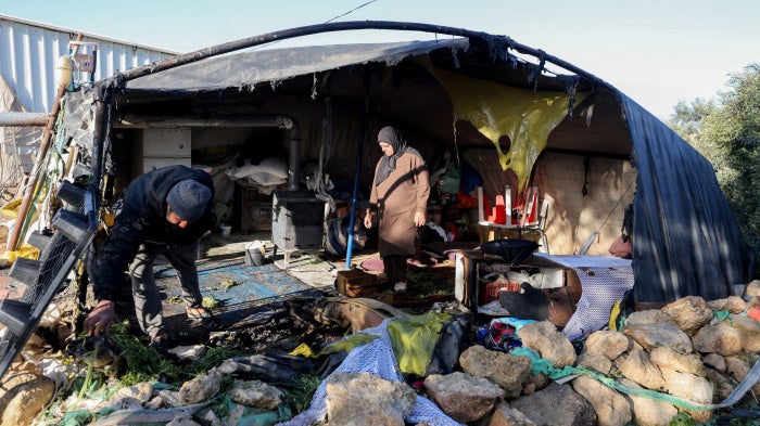 Residents inspect damaged belongings inside a tent burned by suspected Israeli settlers in the village of Susya in Masafer Yatta, south of Hebron, in the Israeli-occupied West Bank, February 25, 2026. 