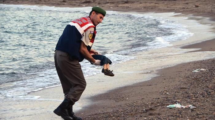 A man carries the body of a dead Syrian boy who died at sea. 