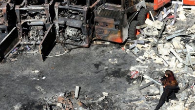 A woman walks in front of charred agricultural equipment, at the site of an Israeli strike in the southern Lebanese village of Msayleh, on October 11, 2025. 