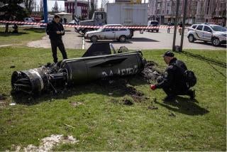 Ukrainian authorities inspect the rocket motor and guidance section of a Tochka-U missile next to the main building of the Kramatorsk train station in eastern Ukraine on April 8, 2022. The phrase “Payback for the children” is painted in Russian on the missile. 
