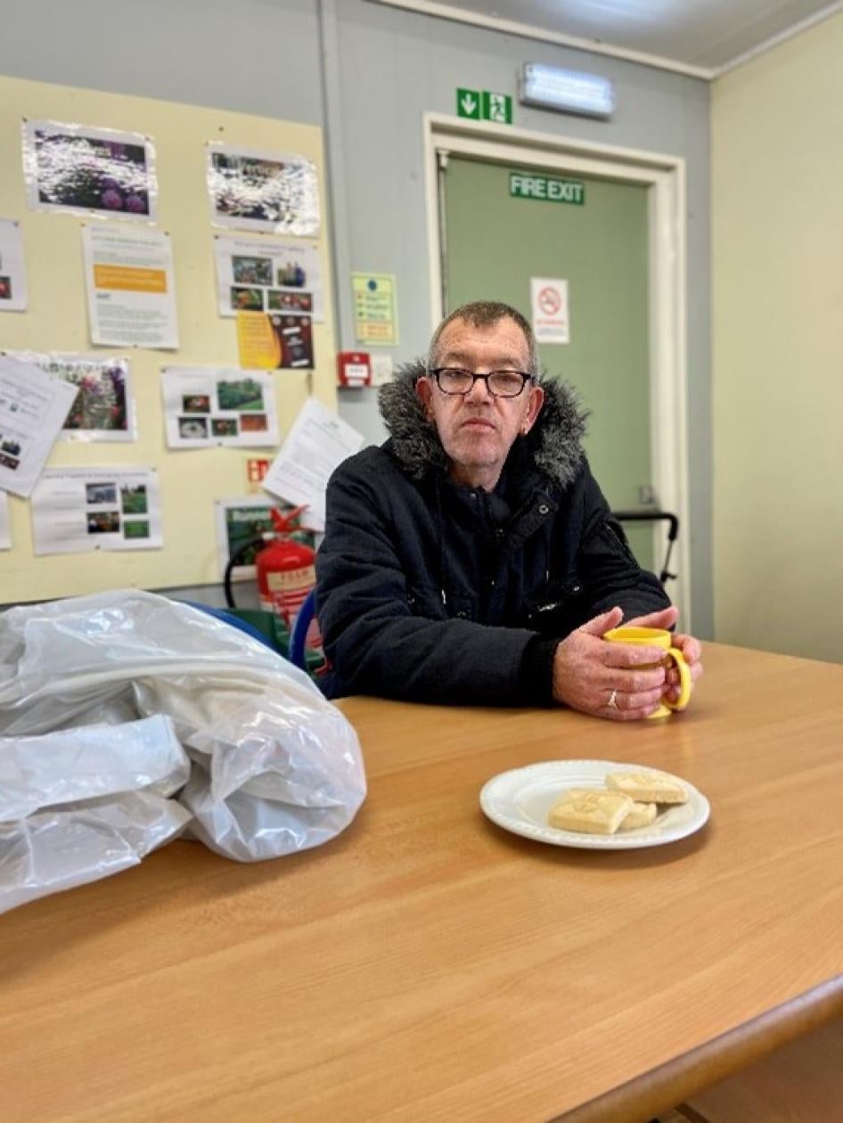 A man in glasses and a coat sits in front of a table