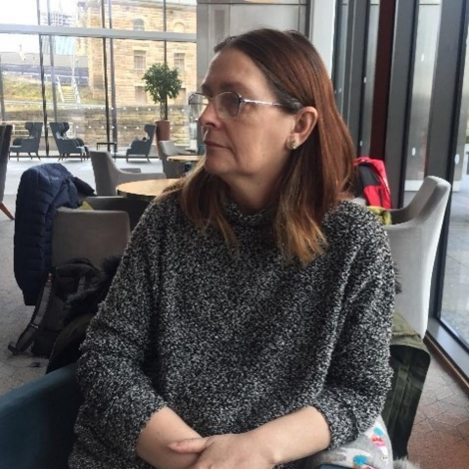 A woman in a gray sweater looks away from the camera