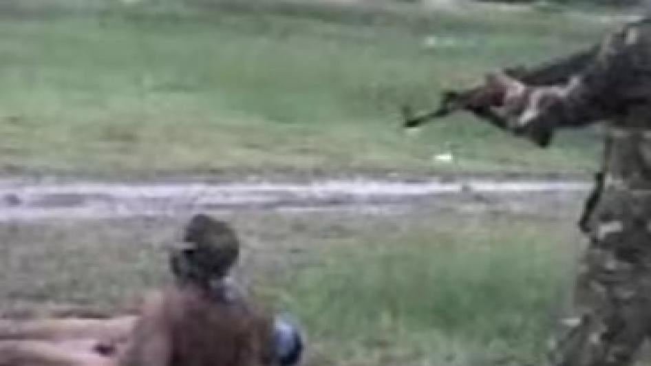 A man holds a gun to another person's head