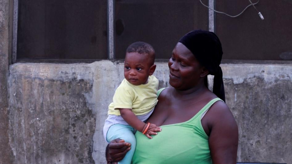 A woman holding a baby poses for the camera