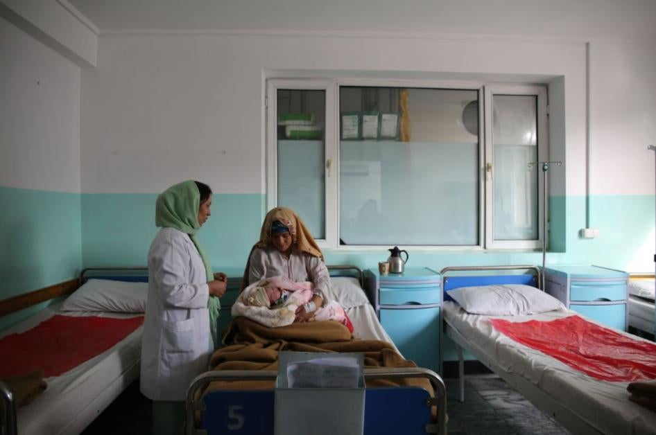 A woman in a hospital bed holds a newborn baby.