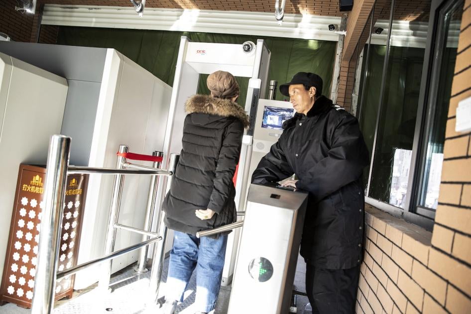 A Chinese security officer watches a woman pass through a checkpoint, equipped with a metal detector and facial recognition technology, to enter the main bazaar in Urumqi in the Xinjiang region of China.