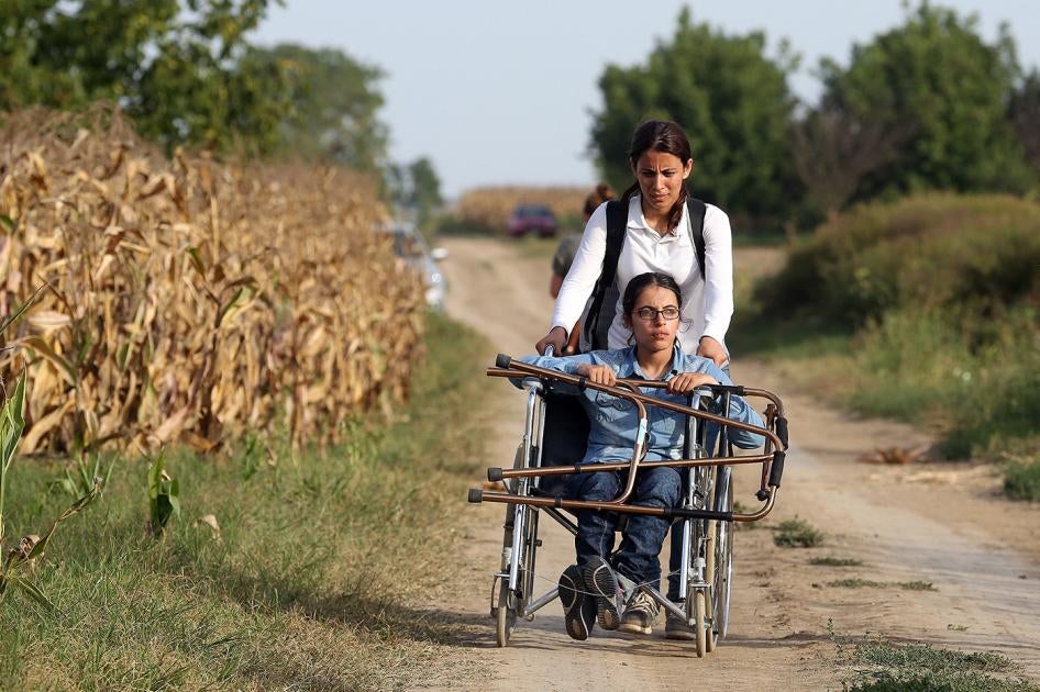 Nujeen, a wheelchair user, and her sister travel down a dirt path after fleeing their native Syria. 