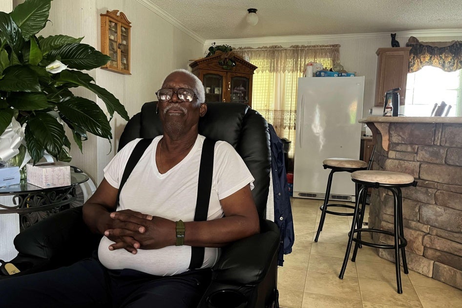 An older man poses for a photo in a chair