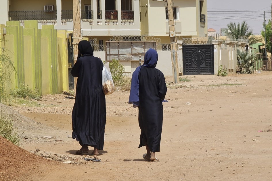 Two unidentifiable women walk down a city street 