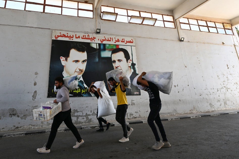 Des Syriens qui s’étaient réfugiés au Liban mais ayant fui ce pays en raison des frappes israéliennes, passaient devant des affiches avec des photos géantes du président syrien Bachar al-Assad au poste frontière de Jusiyeh, dans le sud-ouest de la Syrie (jouxtant la frontière nord-est du Liban), le 2 octobre 2024.  