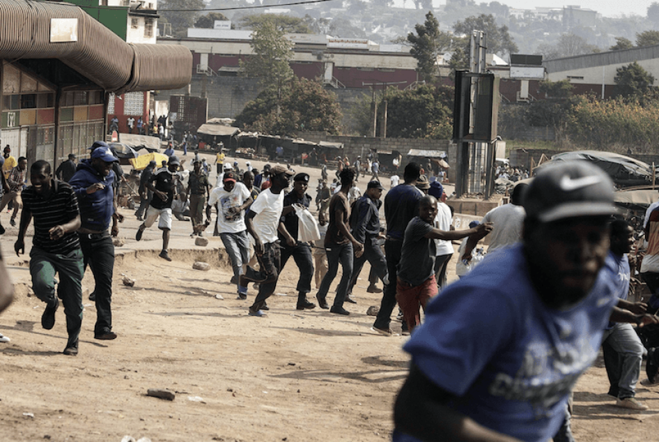 Protesters run for cover as they clash with eSwatini anti-riot police in Manzini, September 19, 2018. Undercurrents of dissent surfaced with trade union protests over low wages by being broken up by riot police. © 2018 GIANLUIGI GUERCIA/AFP/Getty Images