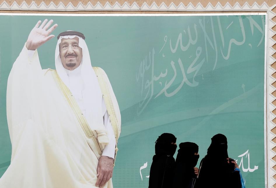 Women walk past a poster of Saudi Arabia's King Salman bin Abdulaziz Al Saud during Janadriyah Cultural Festival on the outskirts of Riyadh, Saudi Arabia February 12, 2018. 