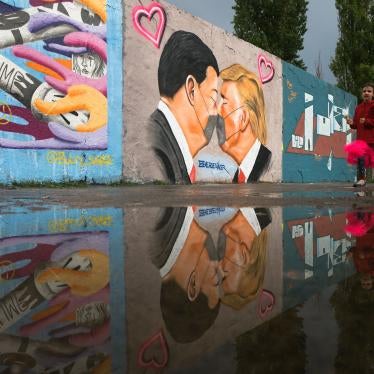 A girl runs in front of graffiti depicting US President Trump and China's President Xi Jinping with face masks displayed on a wall in Berlin, Germany, April 29, 2020.