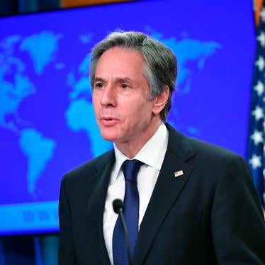 Secretary of State Antony Blinken speaks at the State Department in Washington, standing in front of a world map and a US flag.