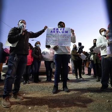 People hold a protest sign that reads "Save asylum" 