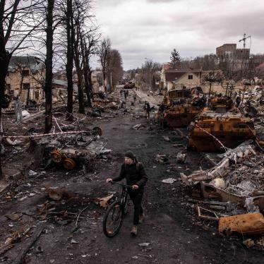 A man pushes his bike through debris and destroyed military vehicles