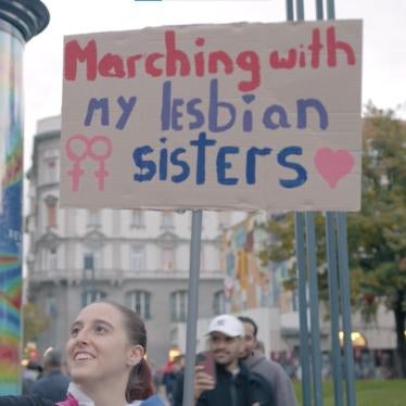 A woman holds a protest sign that says "Marching with my lesbian sisters"