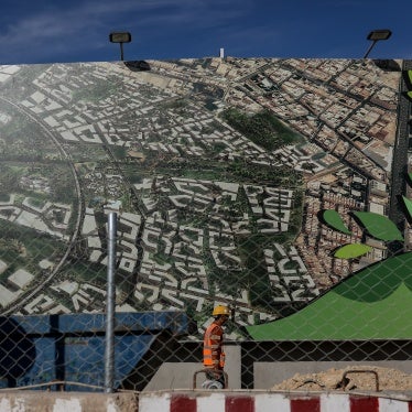 A construction worker passes an advertisement for the King Salman Park gardens and canals development in Riyadh