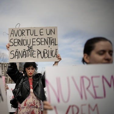A woman holds a banner that reads "Abortion is an essential public health service" at a rally