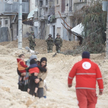 Women carry children as Israeli forces forcibly displace them from Nur Shams refugee camp 