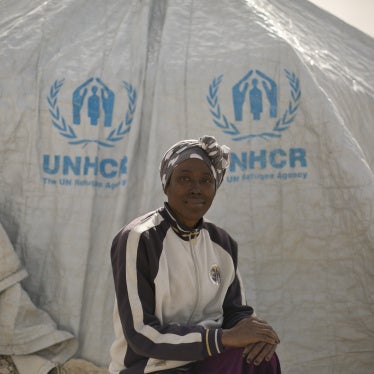 A woman poses for a portrait in front of a UNHCR tent