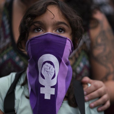 A girl wearing a purple face bandana at a march