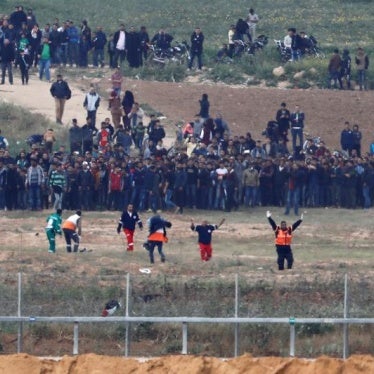 Palestinian paramedics evacuate an injured man on the Gaza side of the Israel-Gaza border, as seen from the Israeli side of the border, during March 30 Land Day demonstrations.