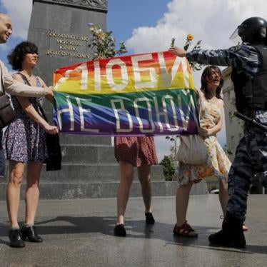 Participants in a LGBT community rally in central Moscow, Russia hold a rainbow flag that reads, "Love. Don't make war", as a policeman stops them.