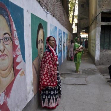 A Bangladeshi woman stands next to a mural displaying a portrait of Bangladesh Prime Minister Sheikh Hasina, left, Dhaka, Bangladesh on December 30, 2018.
